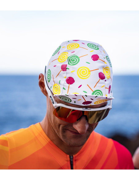 Kolarz ma na głowie czapeczkę rowerową z daszkiem w kolorowe lizaki na całej czapce Luxa