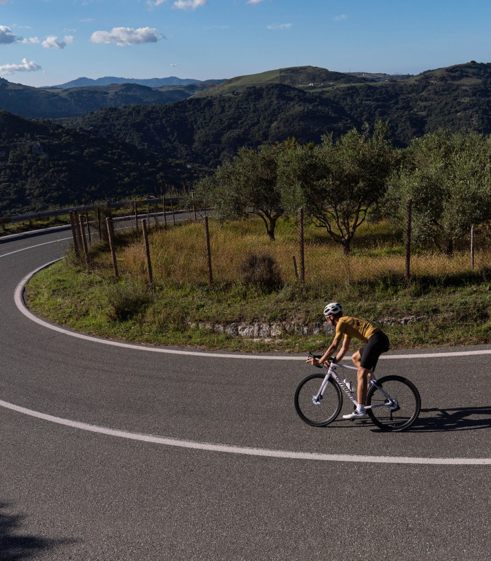 szosowy kolarz jedzie szybko rowerem w stroju kolarskim Luxa i białych krótkich skarpetach
