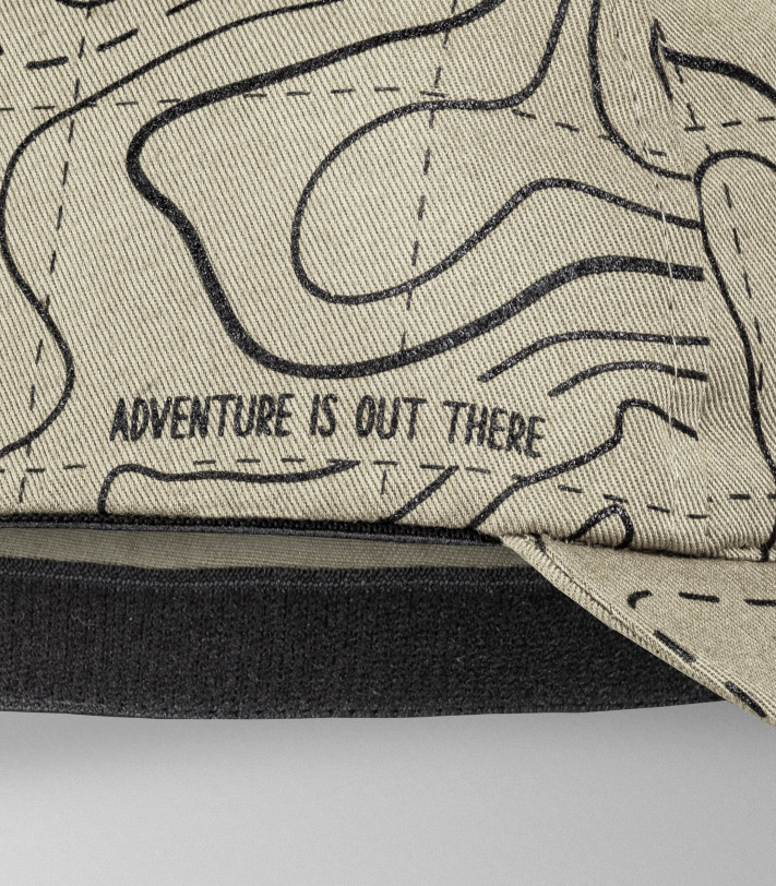 Z boku czapki gravelowej widnieje napis 'Adventure is out there'