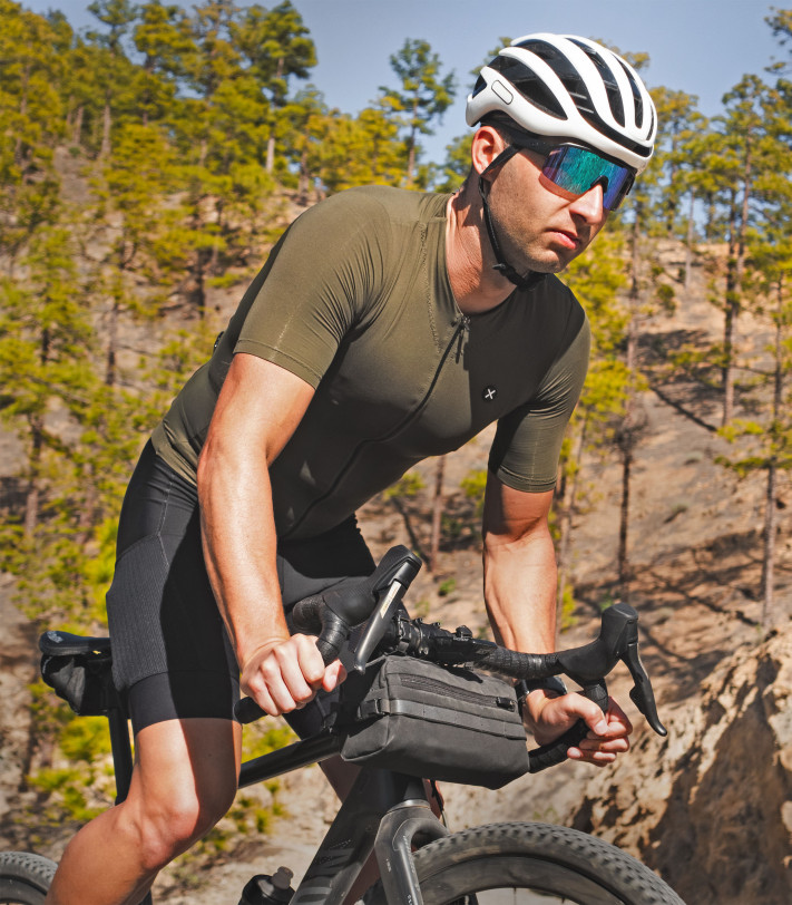 Cyclist wearing Supreme Evergreen jersey on a forest trail