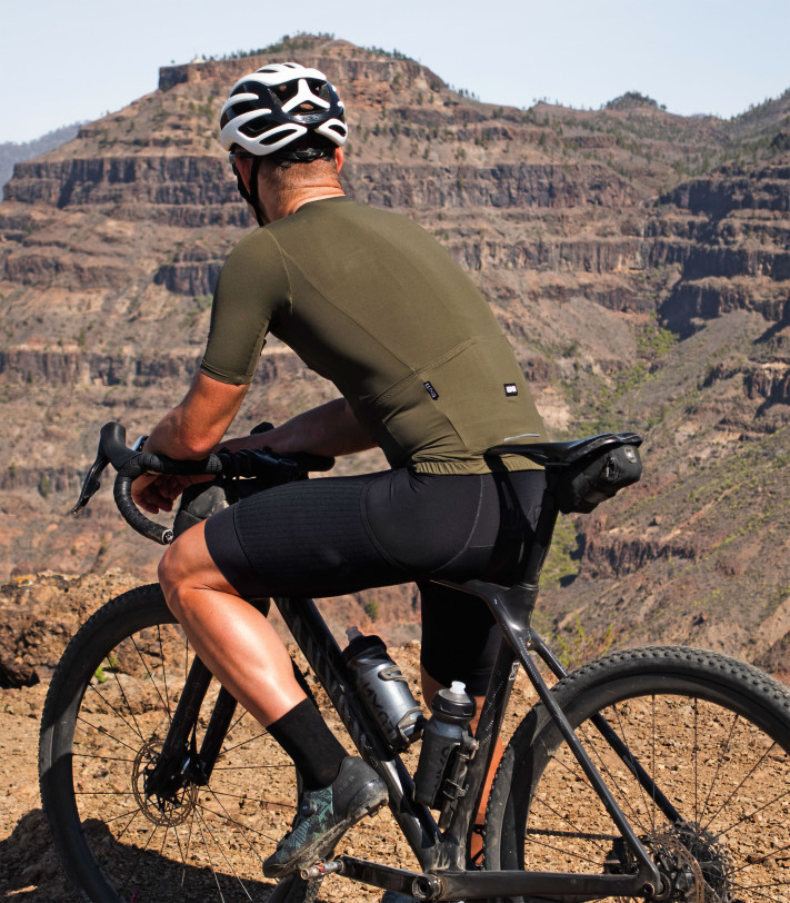 Cyclist wearing Supreme Evergreen jersey on a mountain route