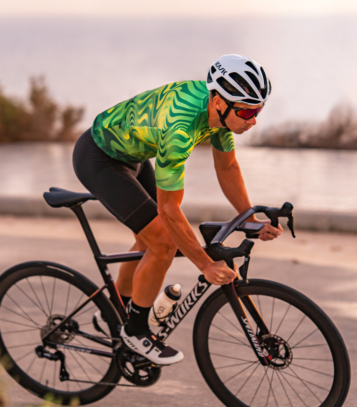 Kolarz w zielonej koszulce kolarskiej Pulse Burst podczas jazdy po szosie