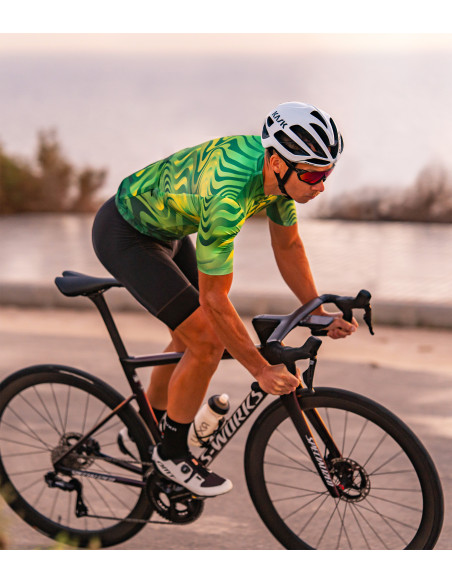 Kolarz w zielonej koszulce kolarskiej Pulse Burst podczas jazdy po szosie