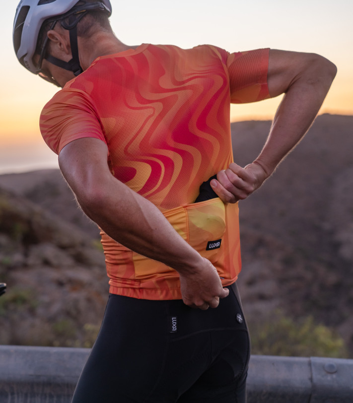 Luxa Core Ultralight Black jacket - cyclist packing the jacket into jersey pocket