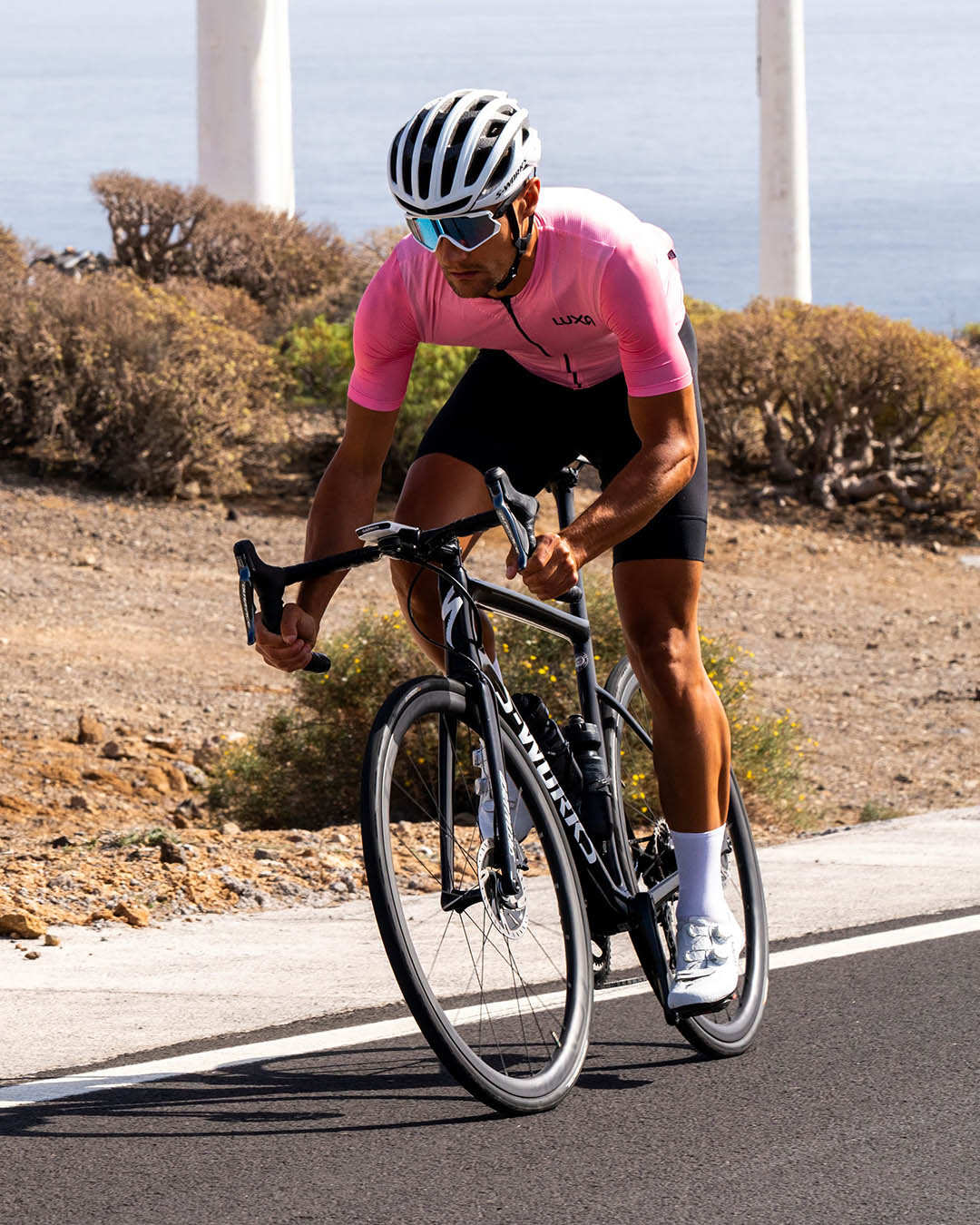 Road cyclist in pink Luxa jersey and black bib shorts
