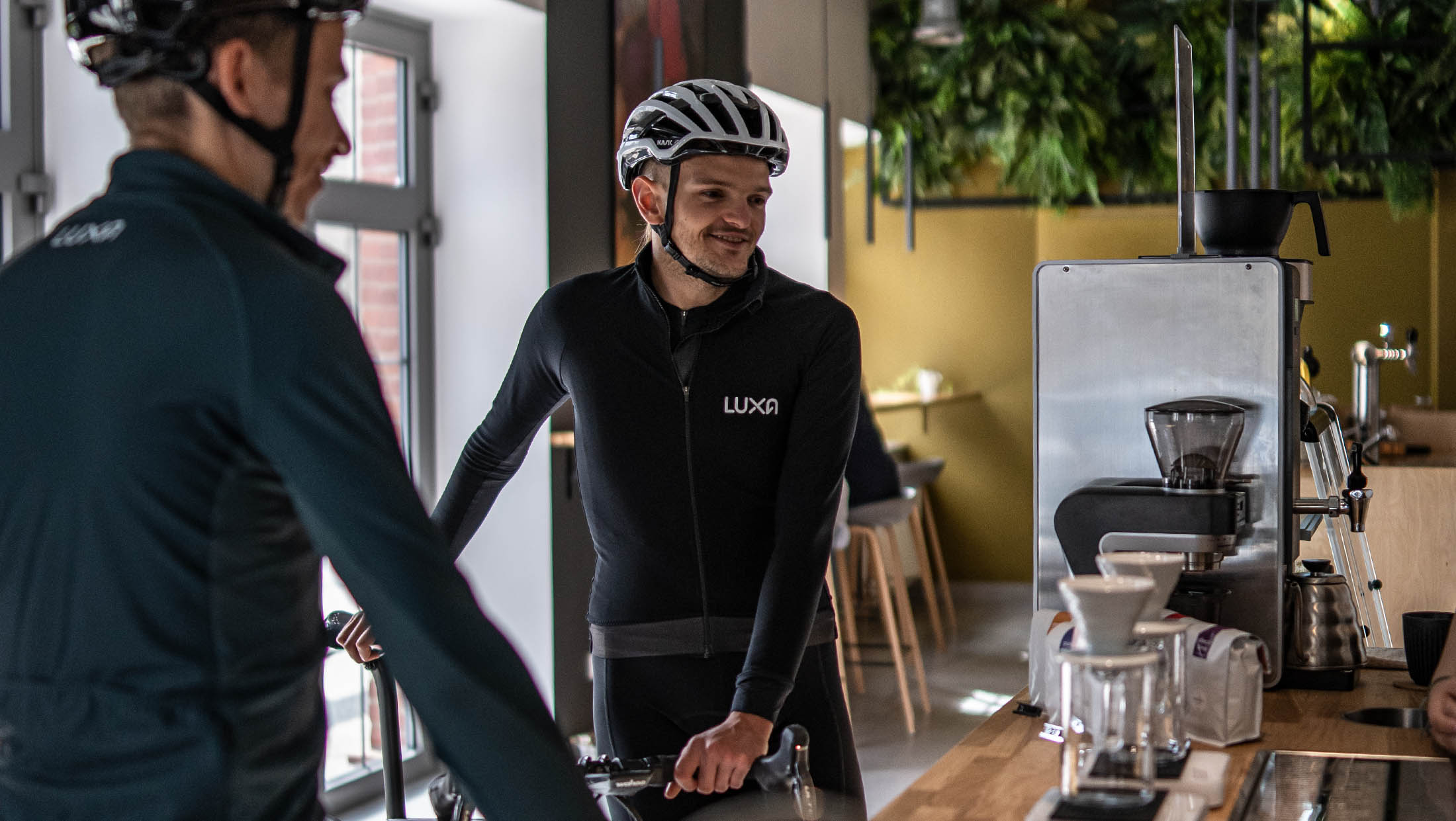 Two cyclists wear Luxa and order a coffee
